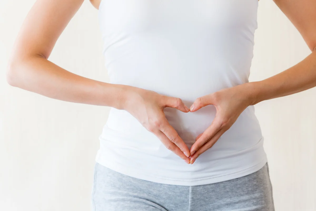 Hände formen ein Herz vor dem Bauch