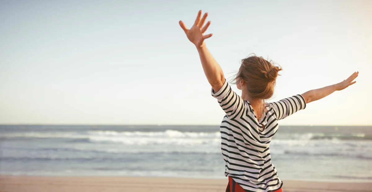 Frau mit ausgebreiteten Armen am Meer