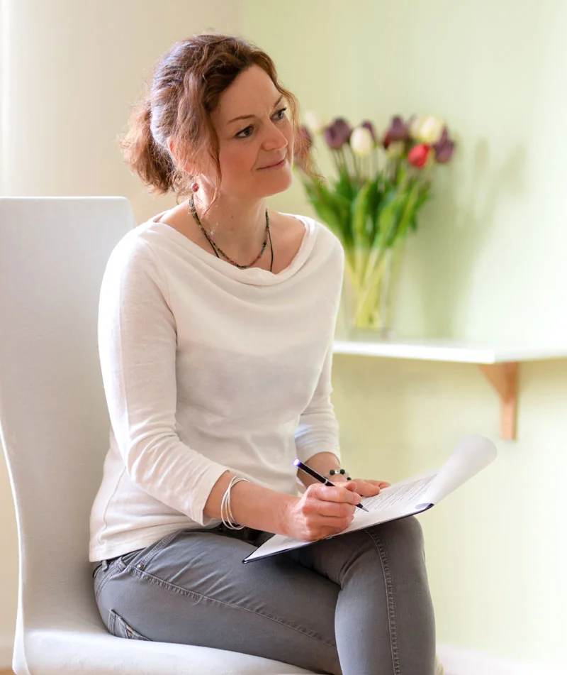 Connie Kiock sitzt mit Notizen auf einem Stuhl in ihrer Praxis